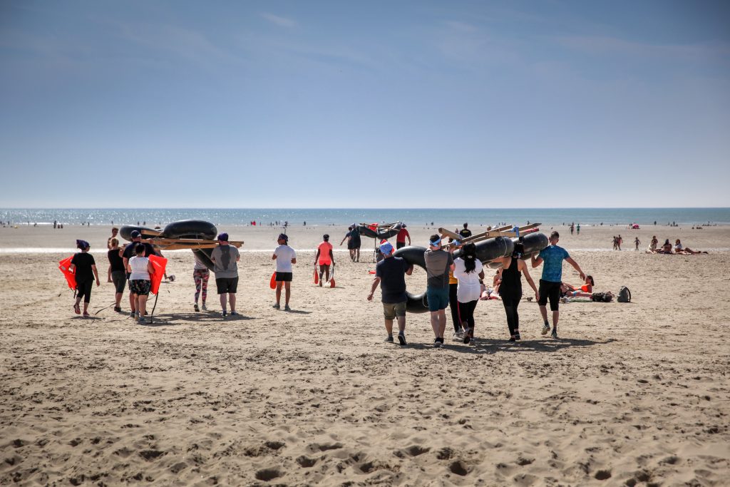 Collaborateurs sur la plage avec une structure en bois et en pneus allant vers l'eau
